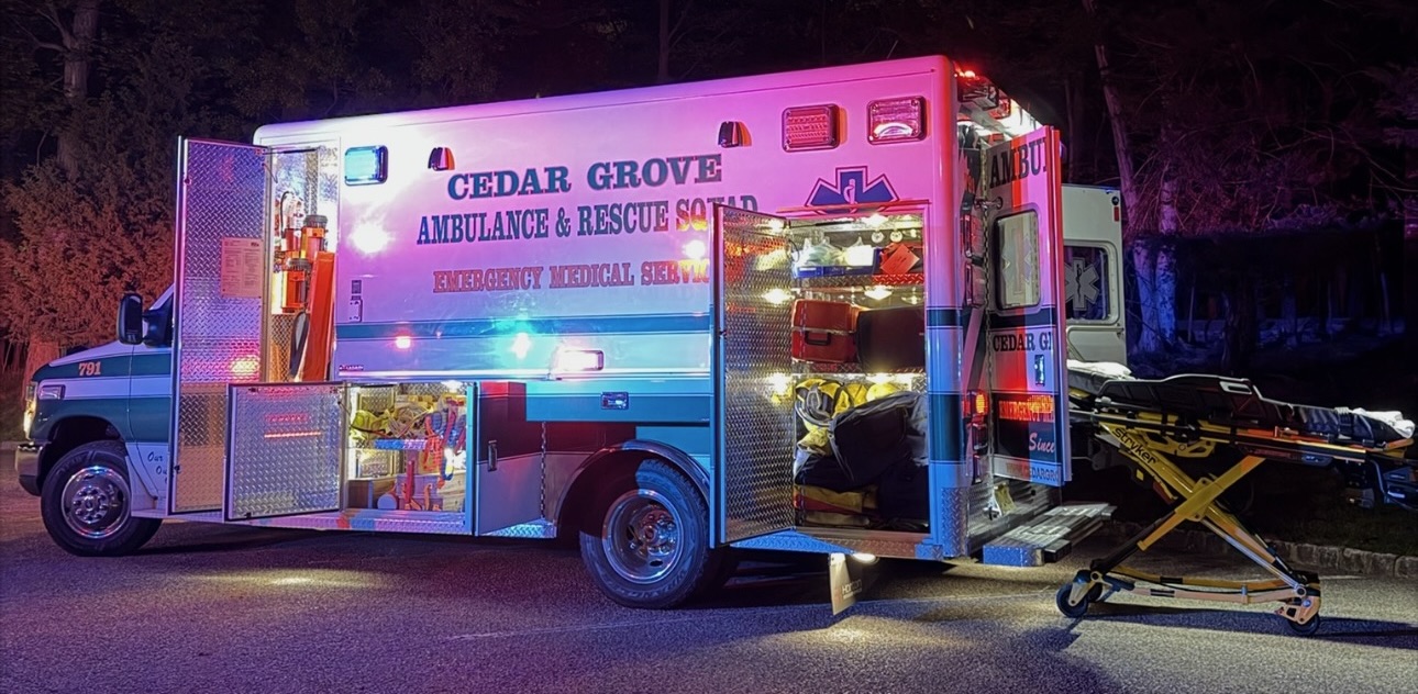 Cedar Grove ambulance with open compartments and stretcher staged at night
