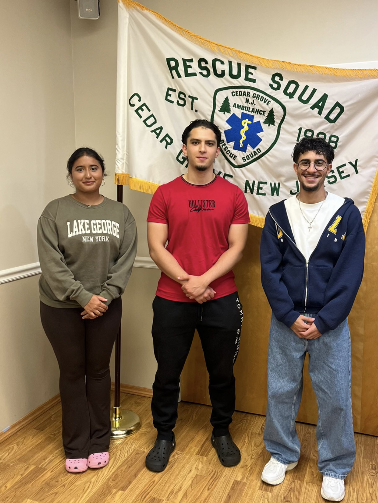 Three members standing in front of a Cedar Grove Rescue Squad flag